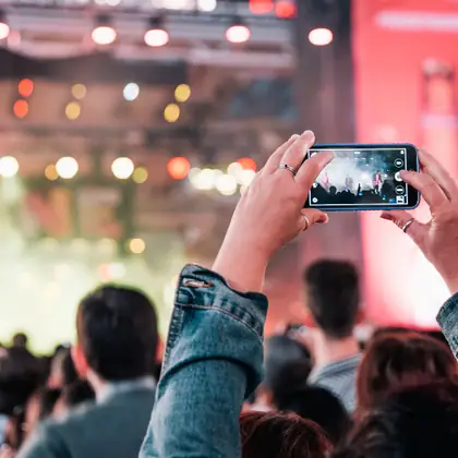 Crowd filming an outdoor stage
